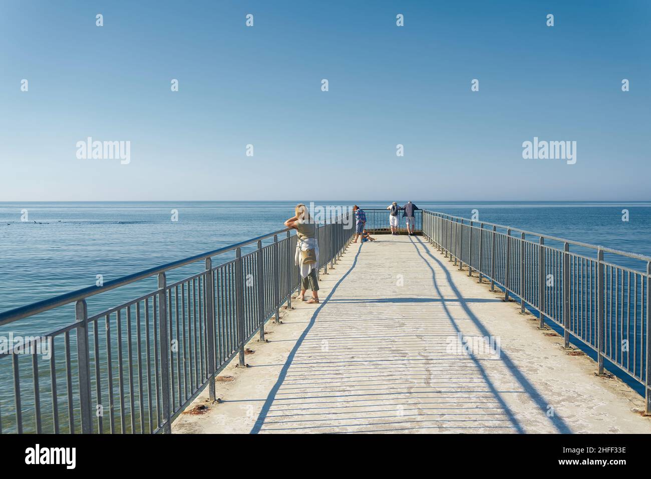 Holidaymakers on the small pier (Male Molo) on the beach of Kolobrzeg on the Polish coast of the Baltic Sea Stock Photo