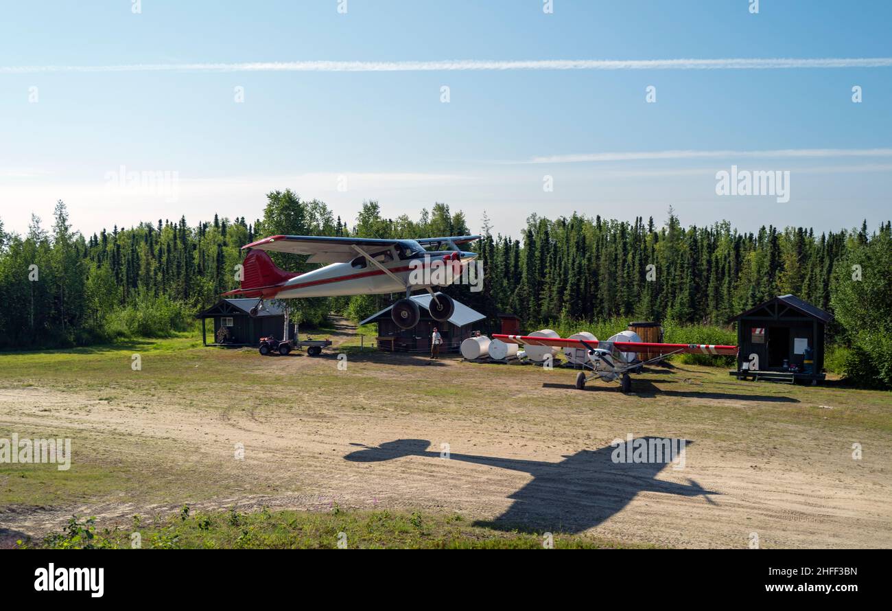 Cessna 170 taking of from the Stony River Lodge dirt strip. Airplane shadow on the ground flying fast than in the air. Stock Photo