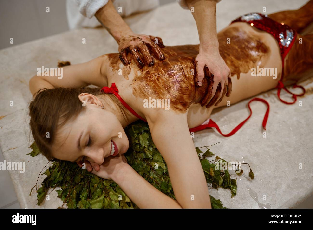 Young woman getting honey massage in sauna Stock Photo