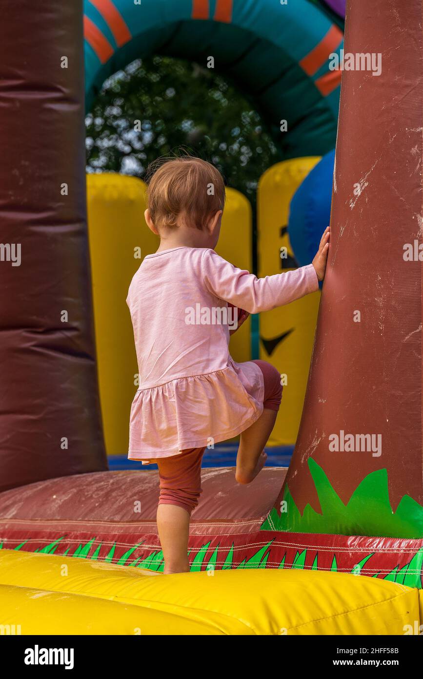little girl on a bouncy castle in the playground Stock Photo