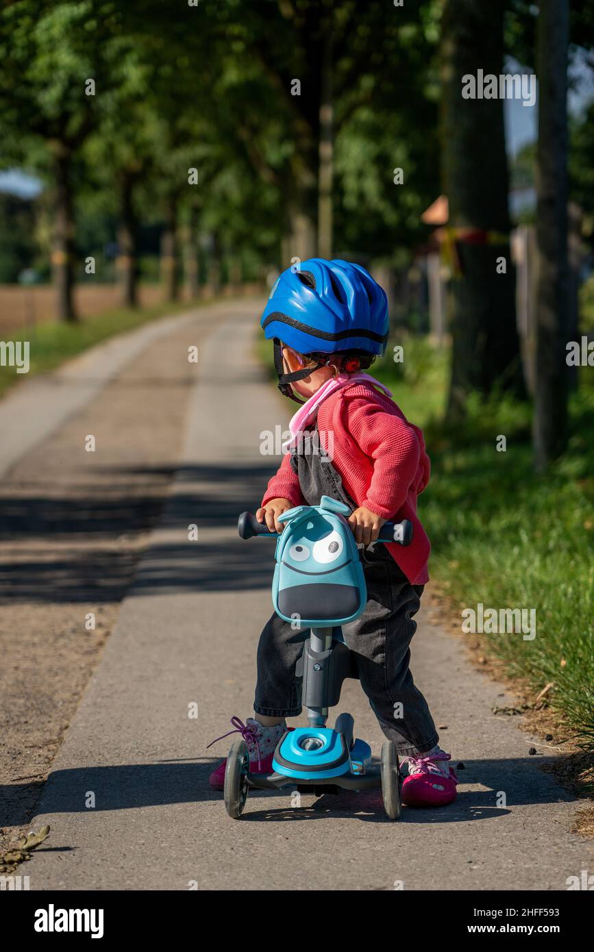 A young child with a blue bicycle helmet on a scooter Stock Photo