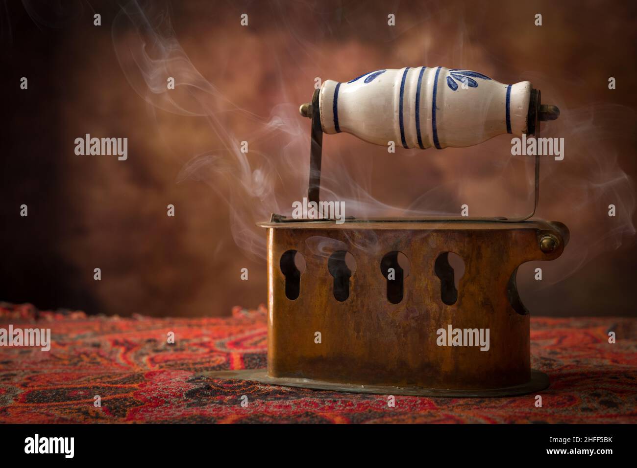 Antique victorian charcoal iron standing on vintage fabric Stock Photo