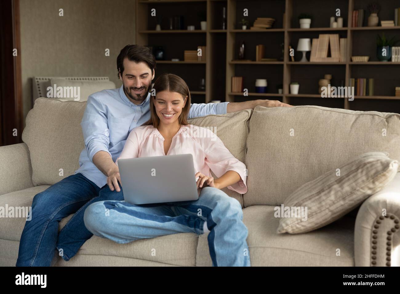 Married couple sit on cozy sofa with laptop Stock Photo