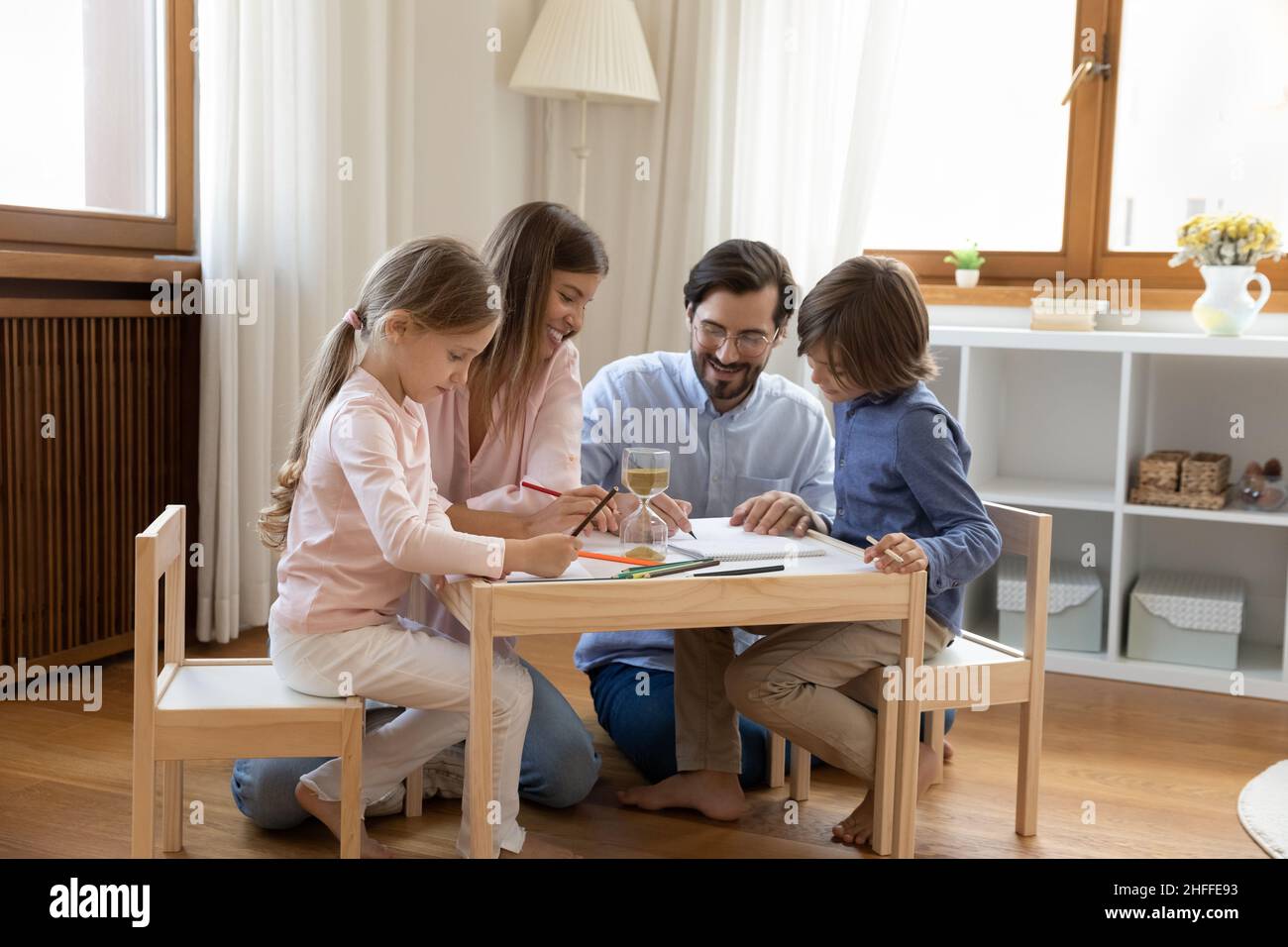 Young parents and kids drawing together sit in modern nursery Stock Photo