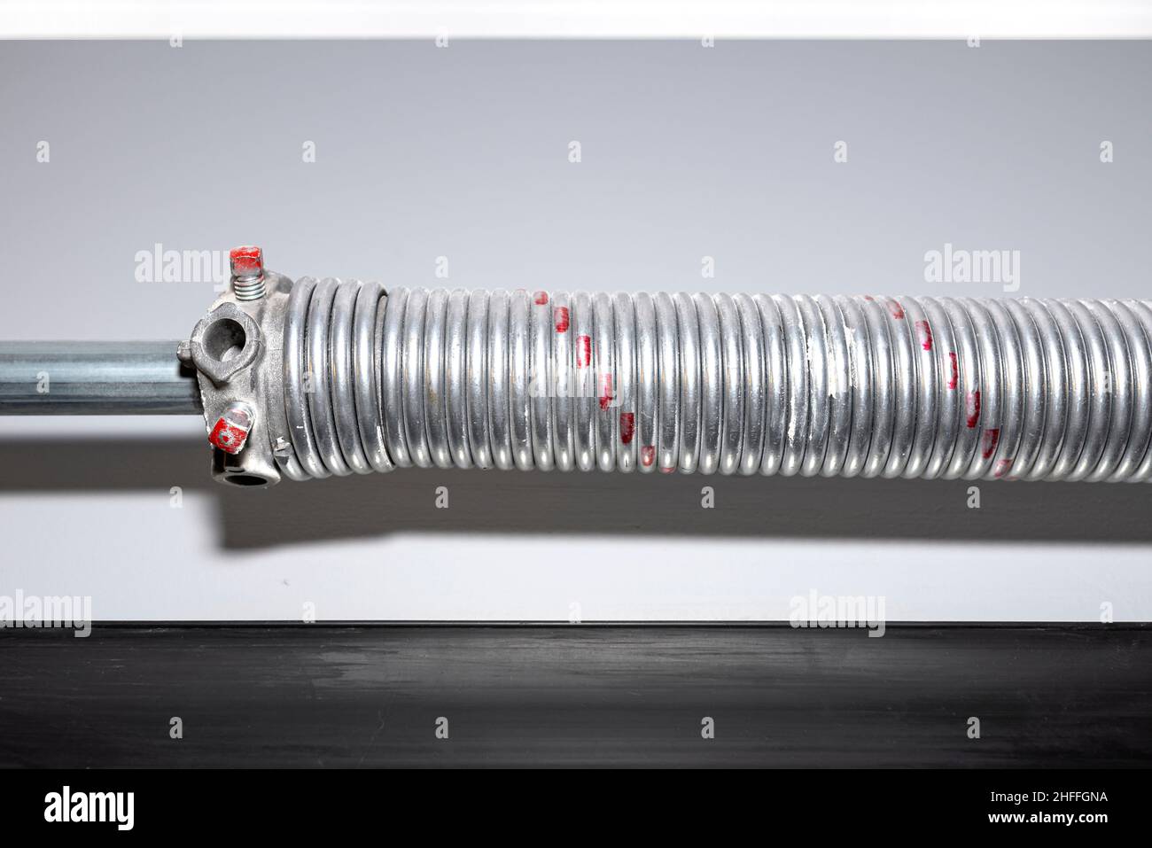 Springs tensioning the garage door mechanism, visible red spring and spring head. Stock Photo