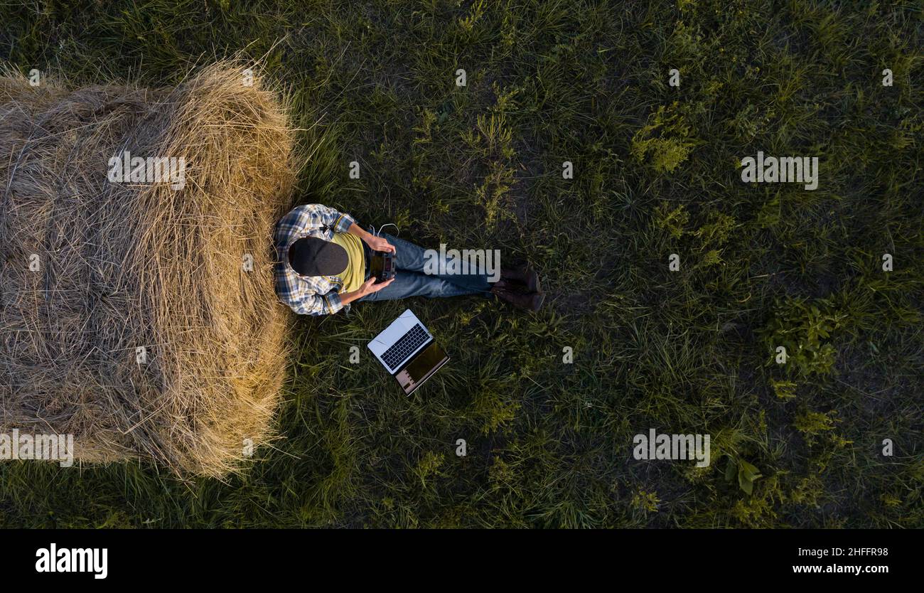 Farmer with laptop on the field. Drone point of view. Smart farming and agriculture digitalization  Stock Photo