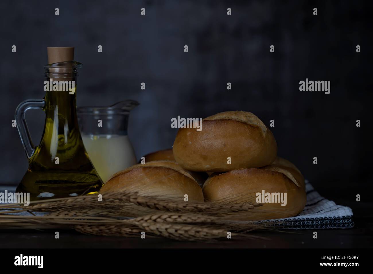 Bread rolls, milk, olive oil on wood table.Breakfast or cooking concept