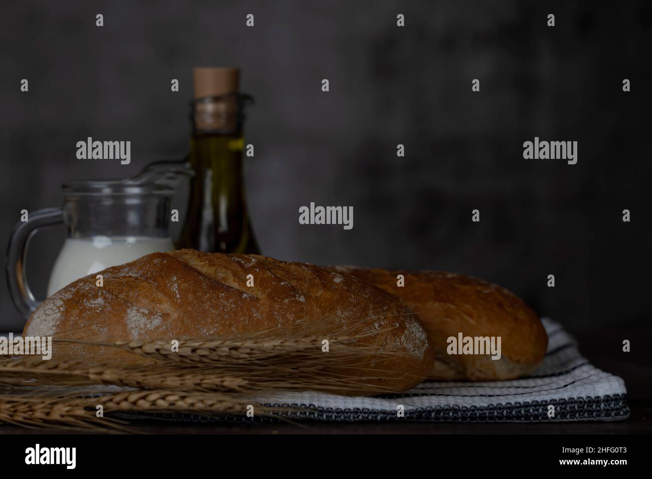 Bread rolls, milk, olive oil on wood table.Breakfast or cooking concept