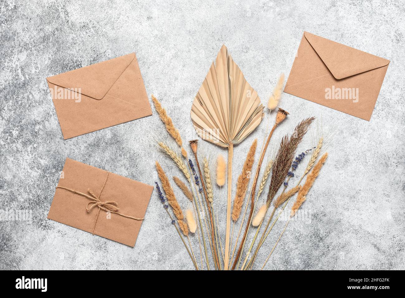 Brown craft envelopes, dry flowers and grass on grunge gray background ...