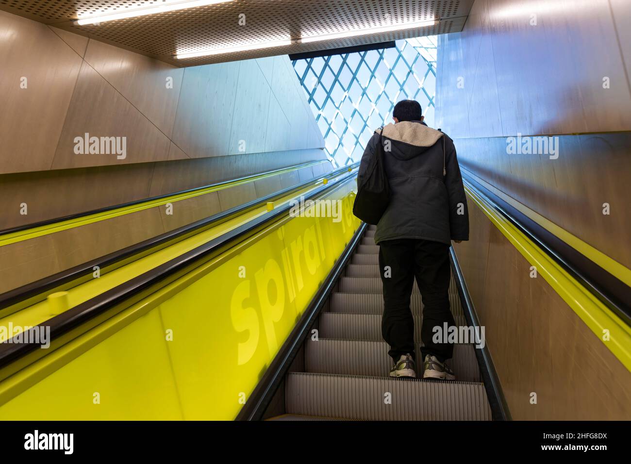 A visitor rides the up escalator to the main level “Living Room” of the Seattle Central Library in downtown Seattle. Stock Photo