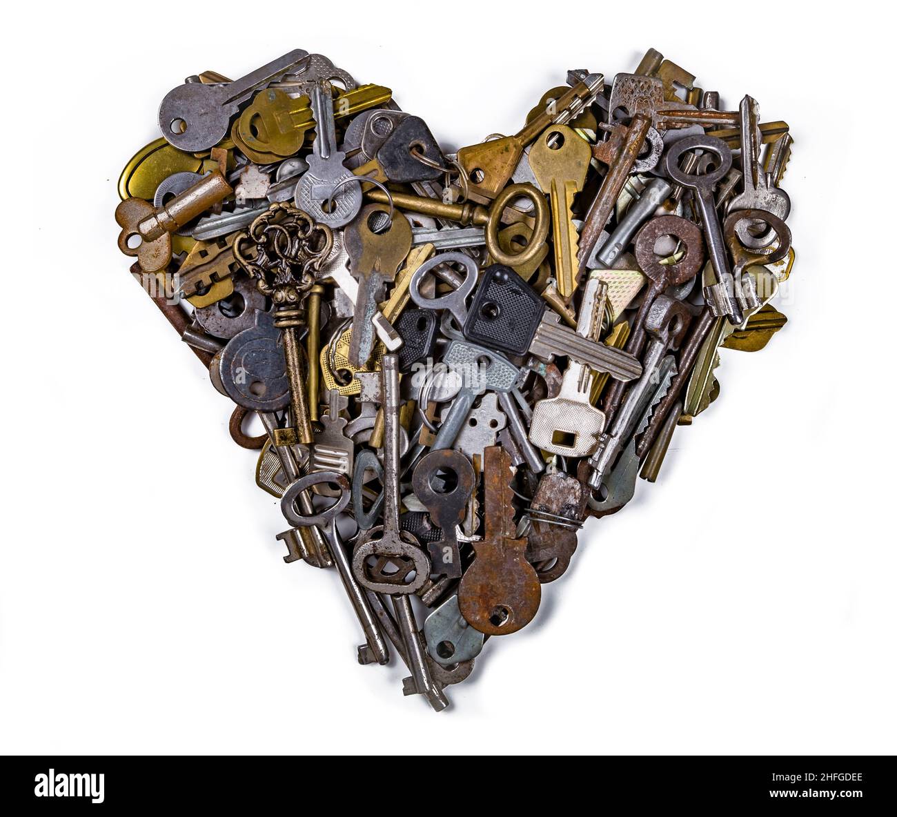 A heart shaped figure isolated on white background laid out from various assorted old multi-colored metal antique keys of different shapes. Home secur Stock Photo