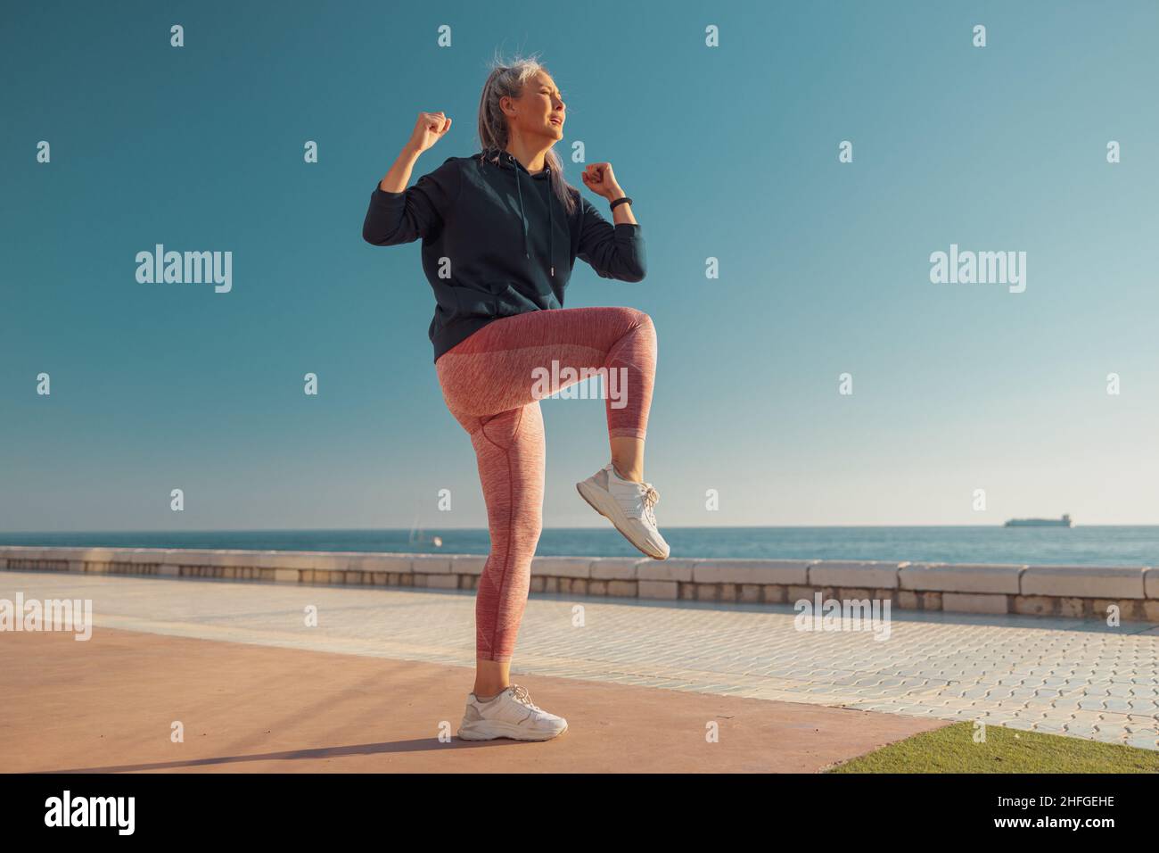 Lady exercising on warm day by the coast Stock Photo