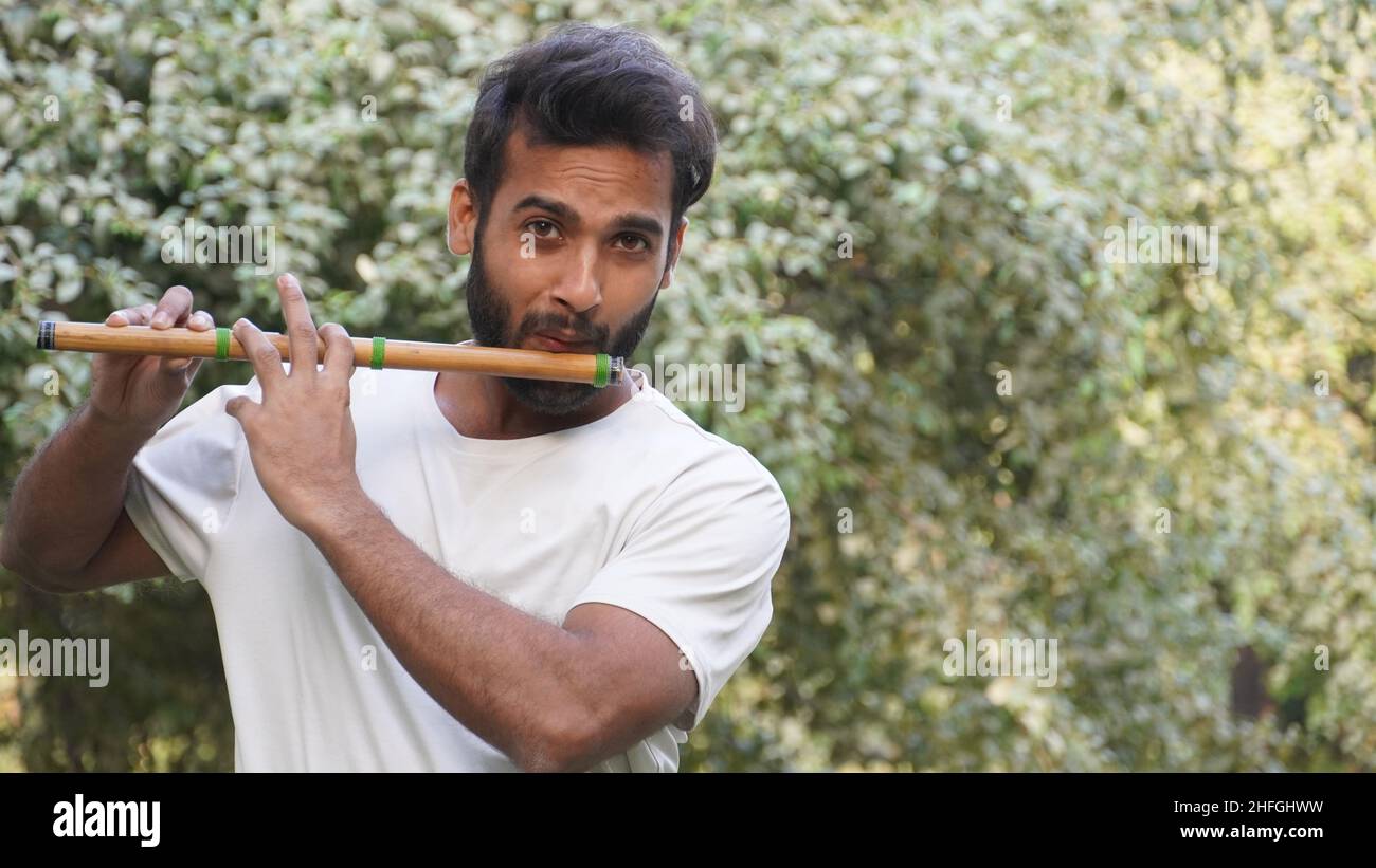 Bansuri player playing music in sunshine at Park Indian Flute Player