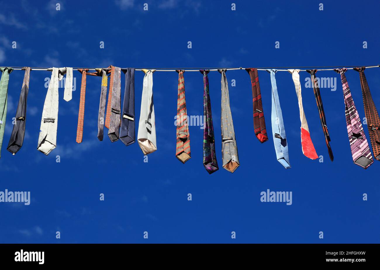 Viele bunte Krawatten hängen an einer Wäscheleine, blauer Himmel  /  Many colorful ties hanging on a clothesline, blue sky Stock Photo