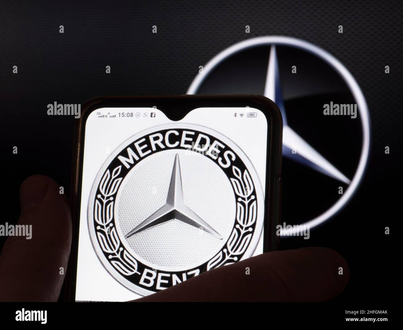 In this photo illustration, the Mercedes-Benz logo is seen displayed on a smartphone screen with the Daimler AG logo in the background. Stock Photo