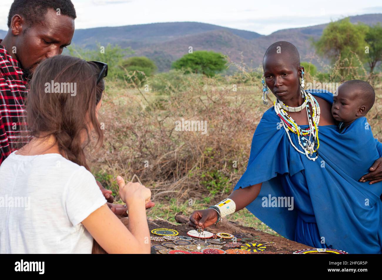 Woman from the Masai tribe offers to buy national souvenirs to a European tourist woman 16.12.2021, Arusha, Tanzania Stock Photo