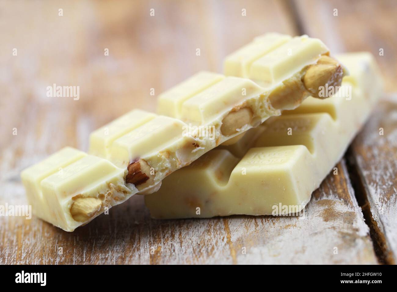 Two pieces of delicious and creamy white chocolates with hazelnuts on rustic wooden surface Stock Photo