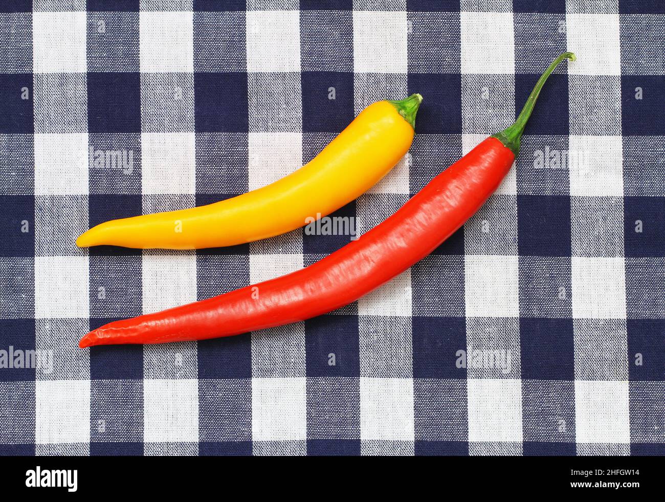 Red and yellow chili on navy blue checkered cloth with copy space Stock Photo