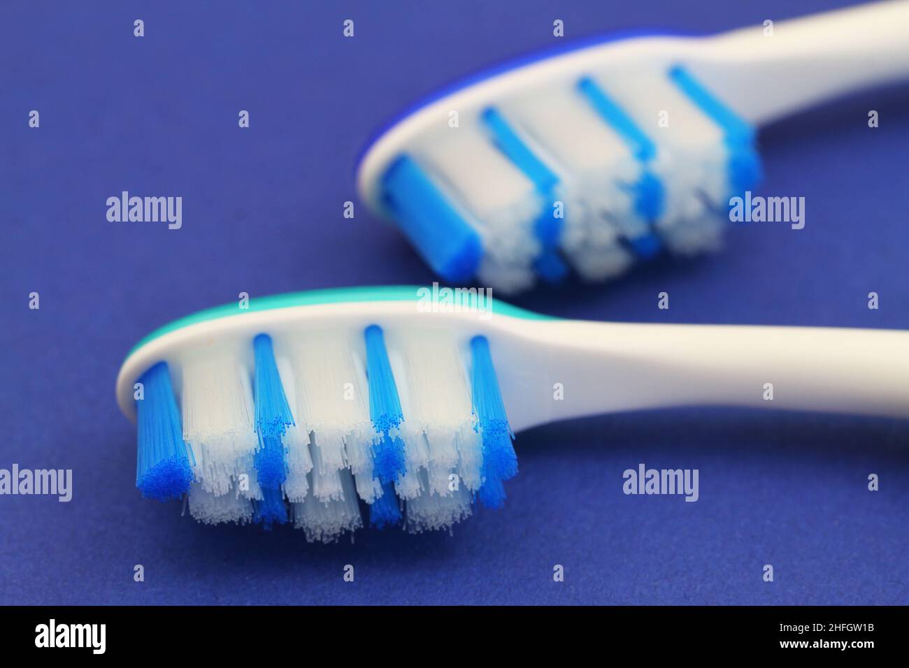 Close up of blue and white toothbrushes on blue background Stock Photo
