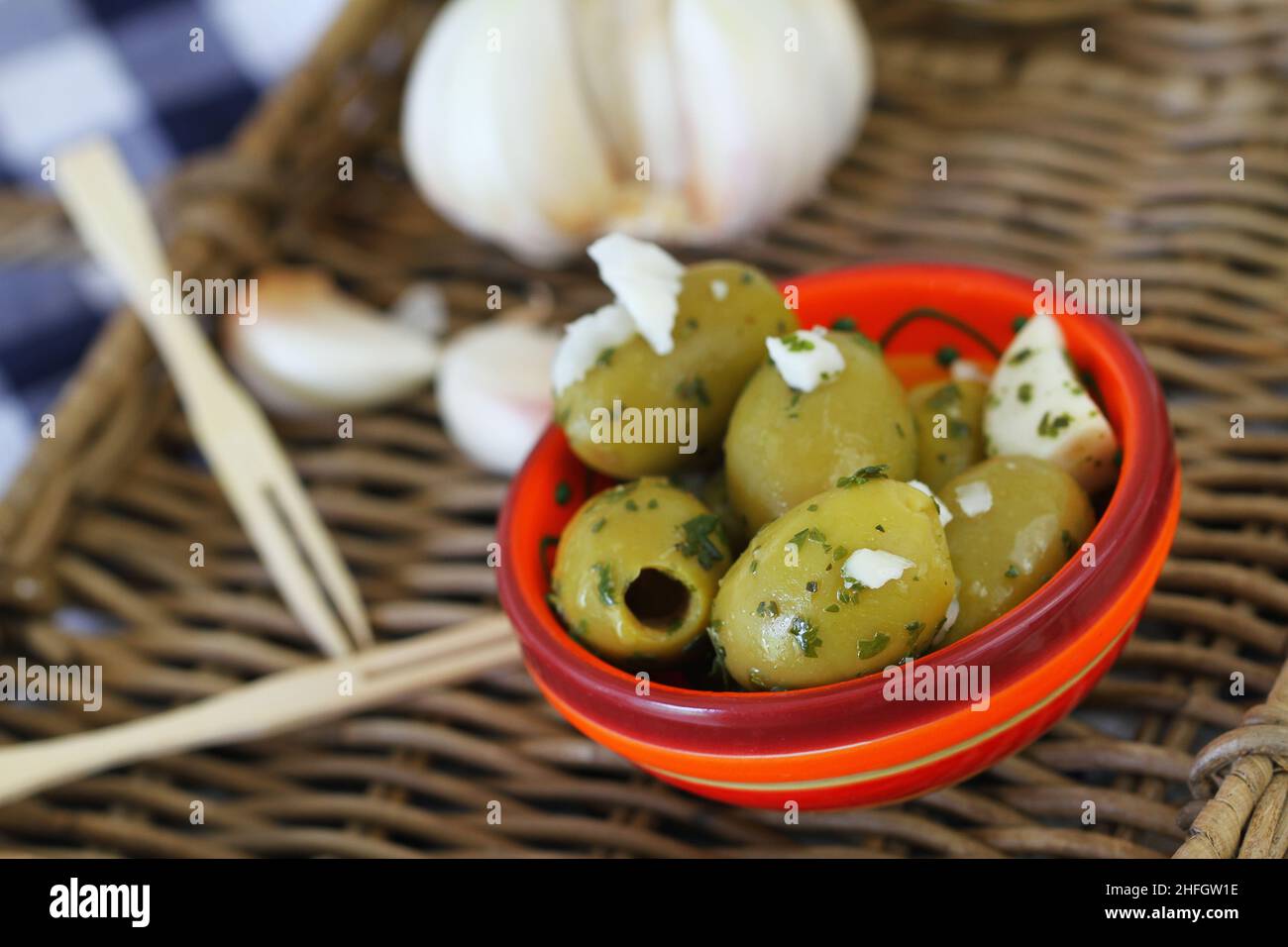 Tasty olives with garlic in colorful clay bowl, close up Stock Photo