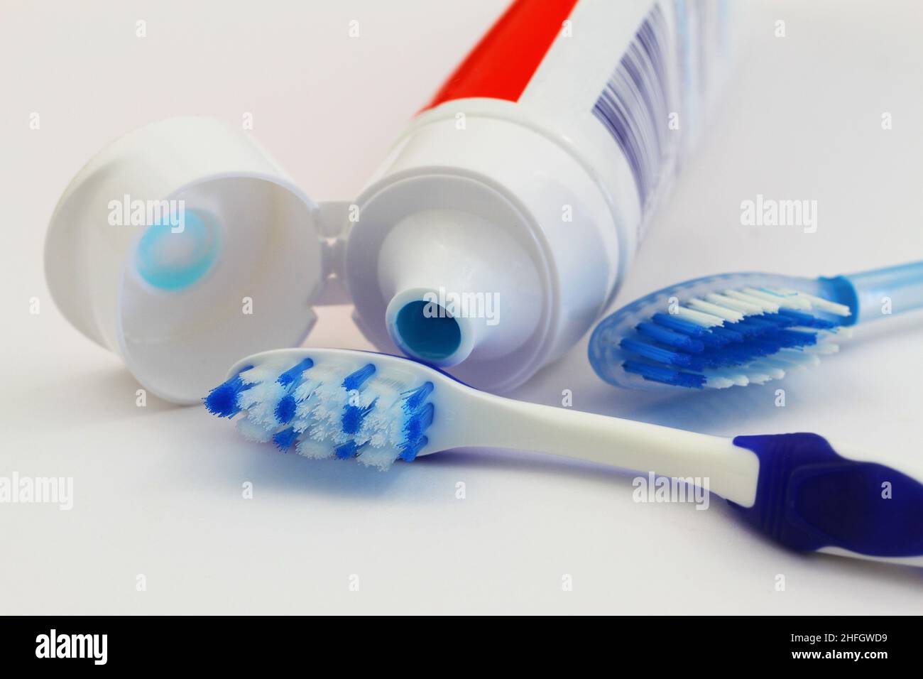 Two blue and white toothbrushes and toothpaste on white background Stock Photo
