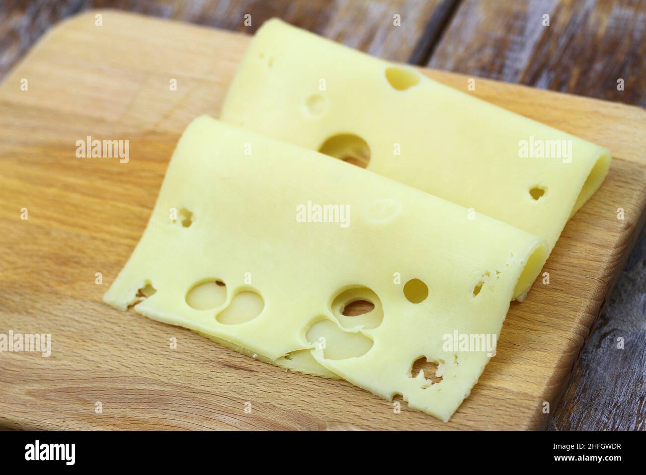 Two slices of Swiss cheese on wooden board Stock Photo
