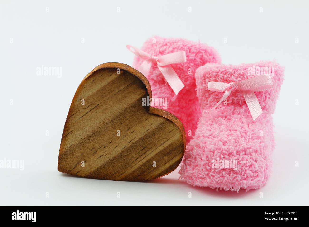 Wooden heart and pink baby booties on white background Stock Photo