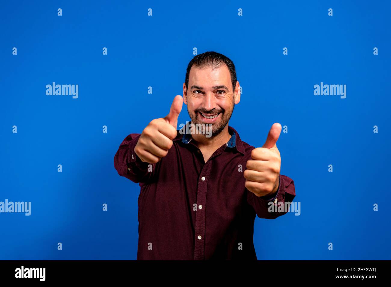 Young handsome man wearing purple shirt approving doing positive ...