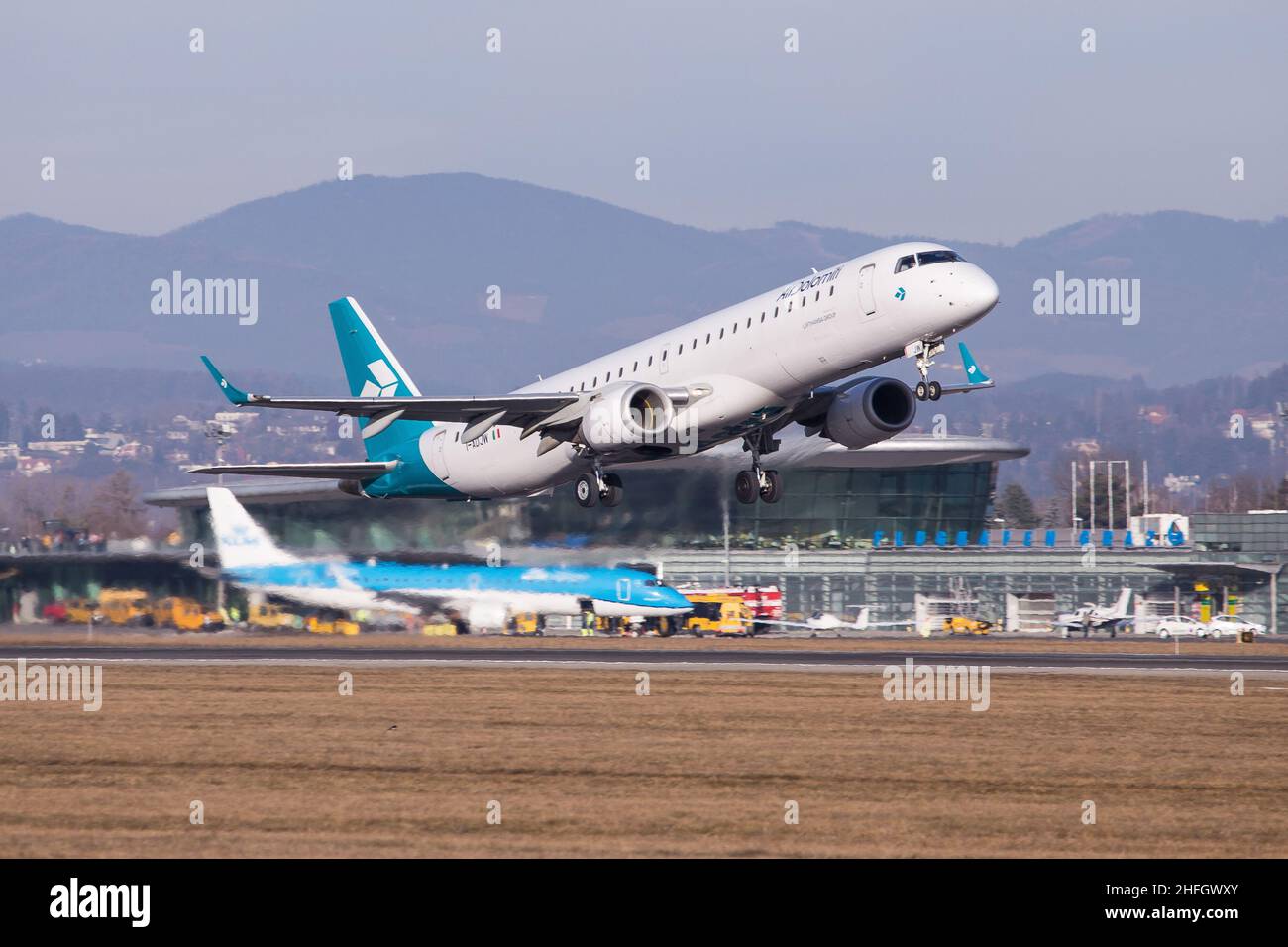 Air Dolomiti of Lufthansa Group Embraer Regional jet departing Graz in Austria for a flight to munich with an airport in the background Stock Photo