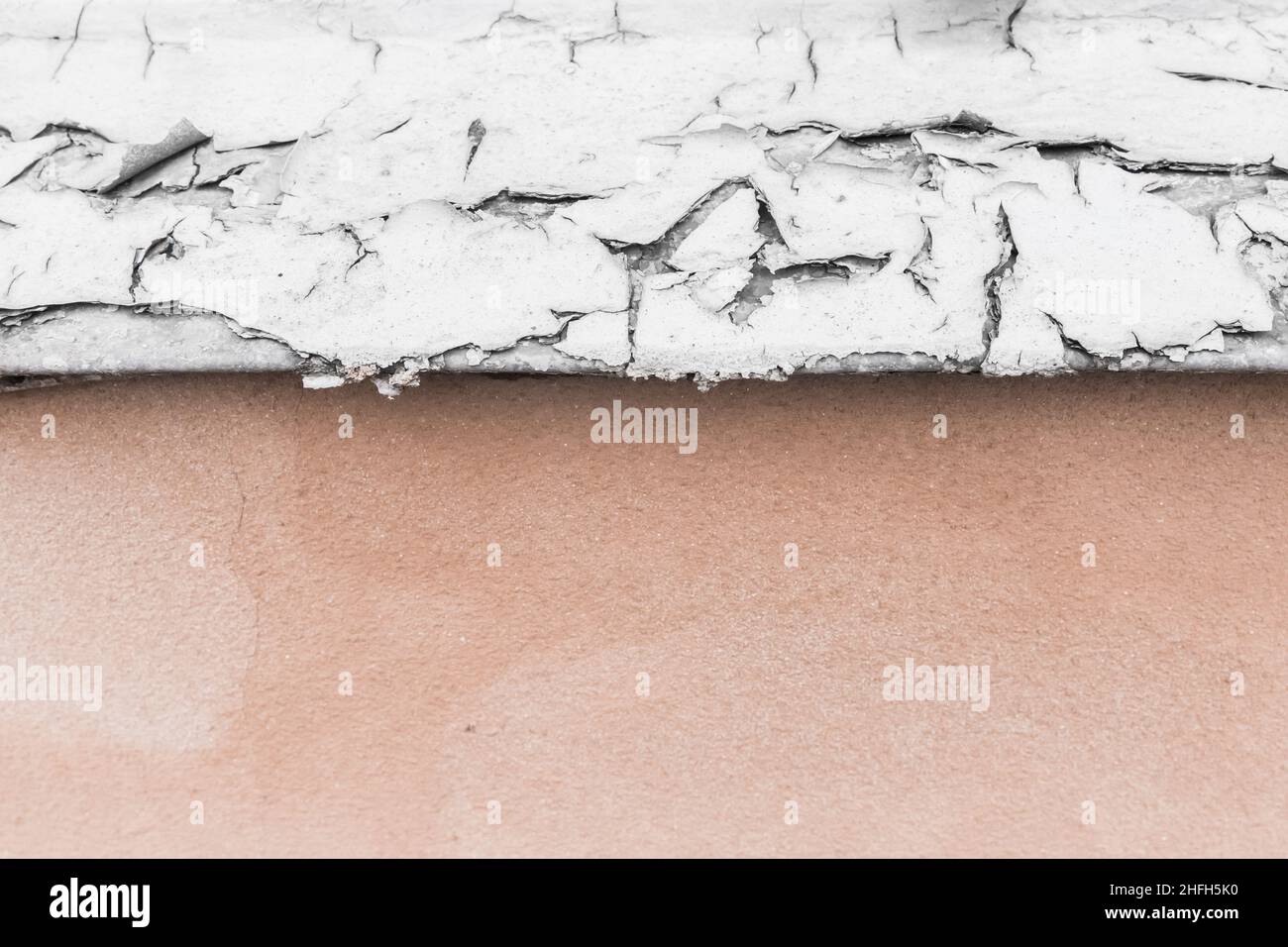 Peeling cracked white paint on an old metal window sill surface wall