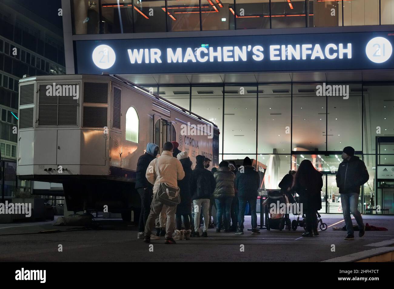 Dortmund, Germany, January 16th, 2022 - People are waiting in front of a test station in a trailer at the Dortmund Football Museum to be tested with a rapid corona antigen test. The neon sign above them says: WE JUST DO IT"  ---   Dortmund, 16.1.2022 - Leute warten vor einer Teststation in einem Trailer am Dortmunder Fußballmuseum, um mit einem Corona-Antigen-Schnelltest getestet zu werden. Stock Photo