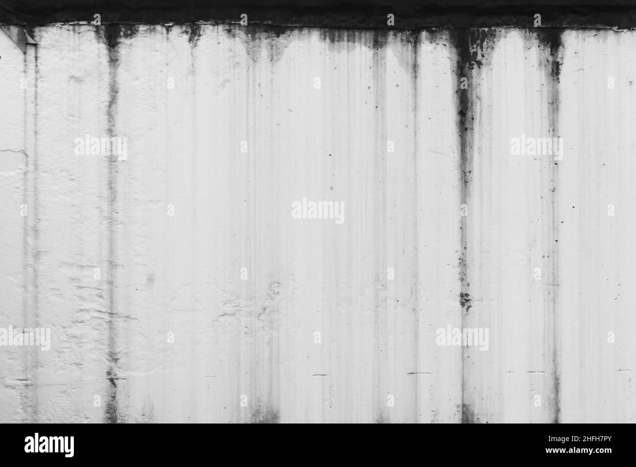 Black dirty spots of fuel oil flow liquid down the white old wall surface chemical industry background. Stock Photo