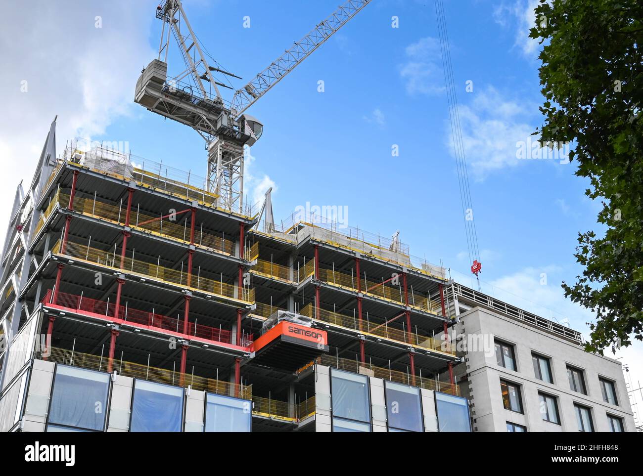 London, England - June 2020: Tower crane working on the side of a tall new building under construction Stock Photo