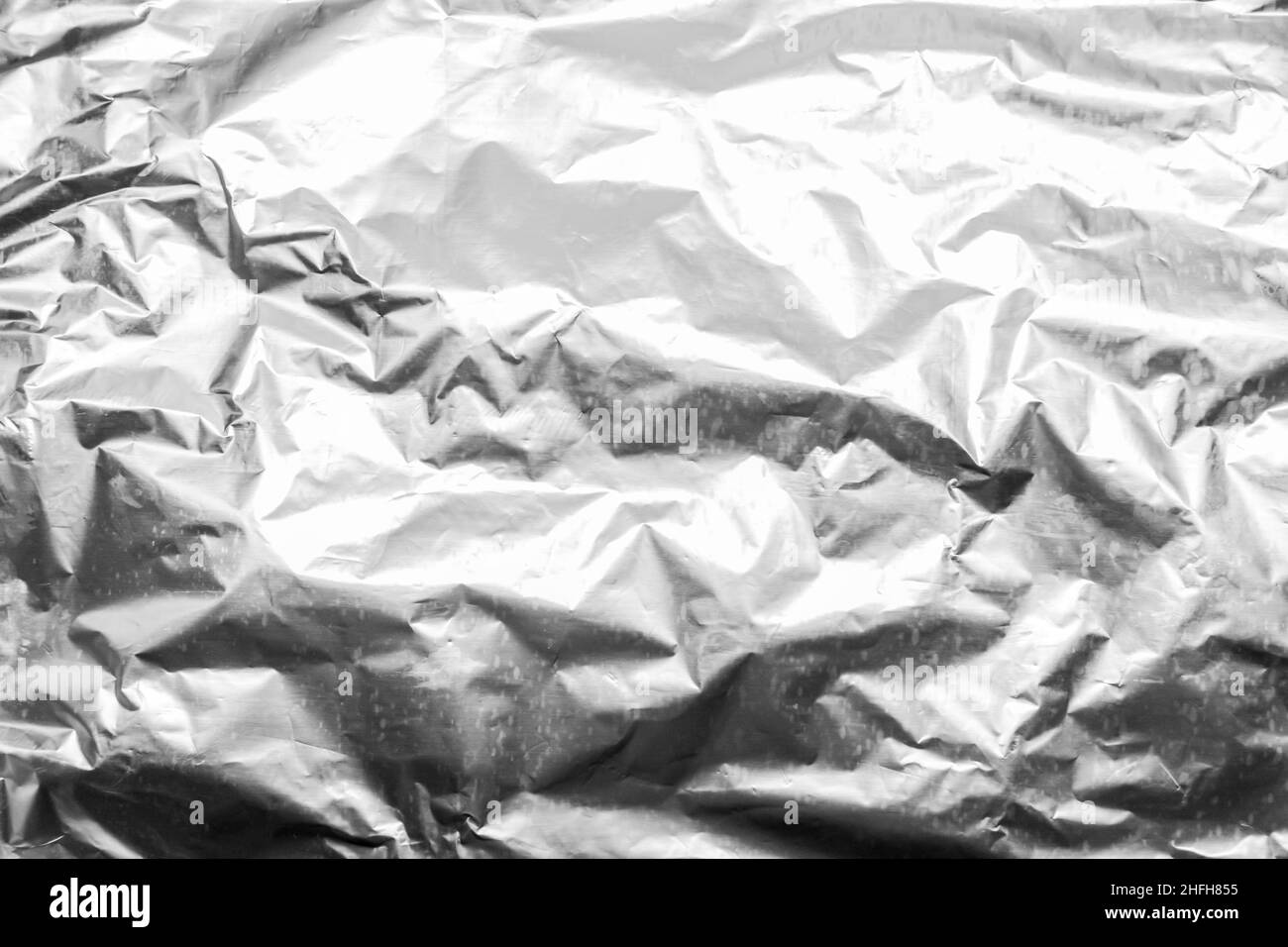 Foil crumpled texture wrinkled silver material abstract pattern surface background. Stock Photo