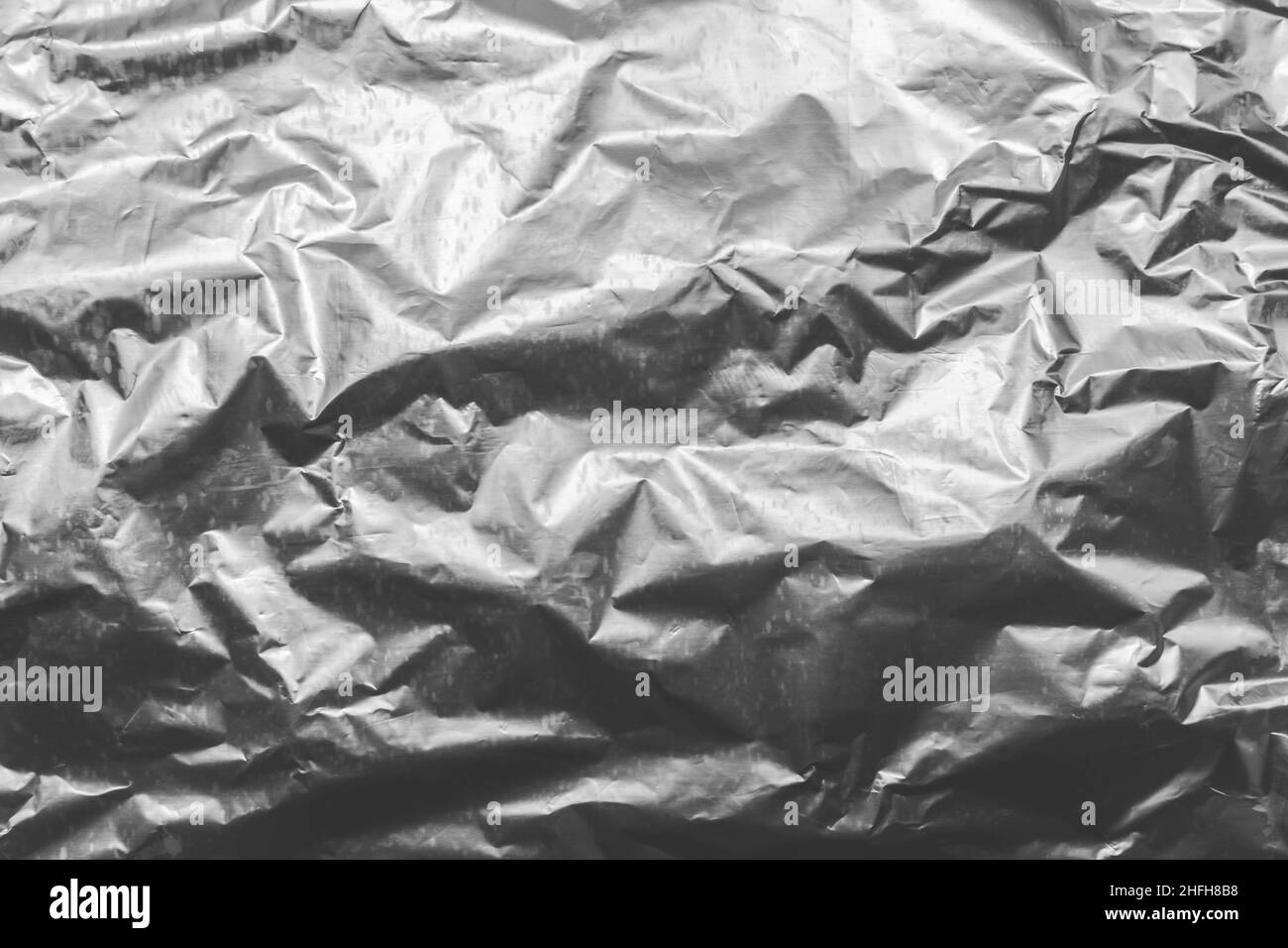 Foil crumpled texture wrinkled silver material abstract pattern surface background. Stock Photo
