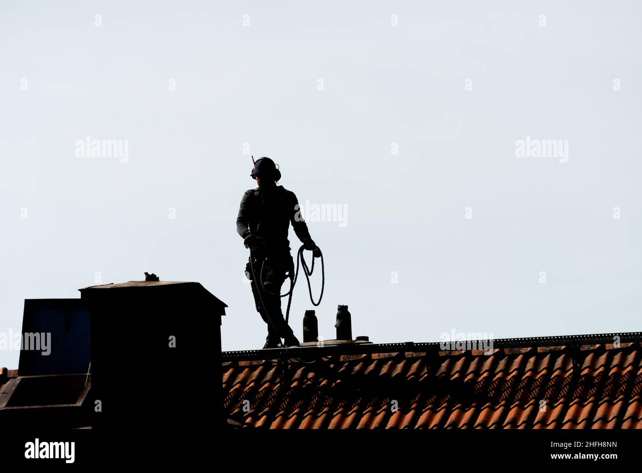 Gothenburg, Sweden - May 06 2020: Silhouette of a chimney sweeper on top of a roof Stock Photo