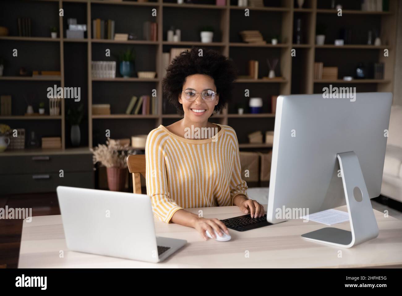 Portrait of happy young African American businesswoman posing in modern office. Stock Photo