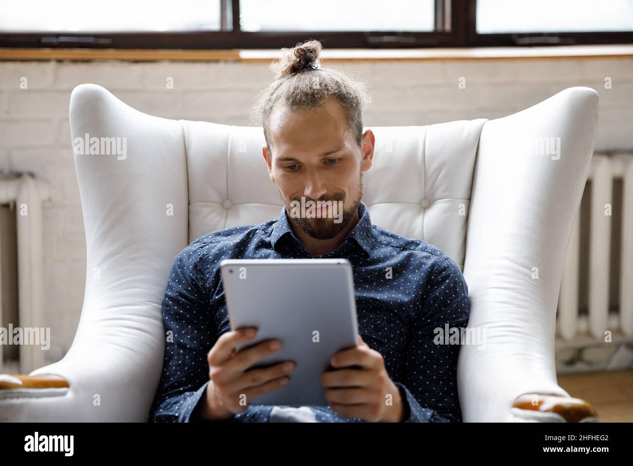 Happy relaxed young man using digital tablet at home. Stock Photo