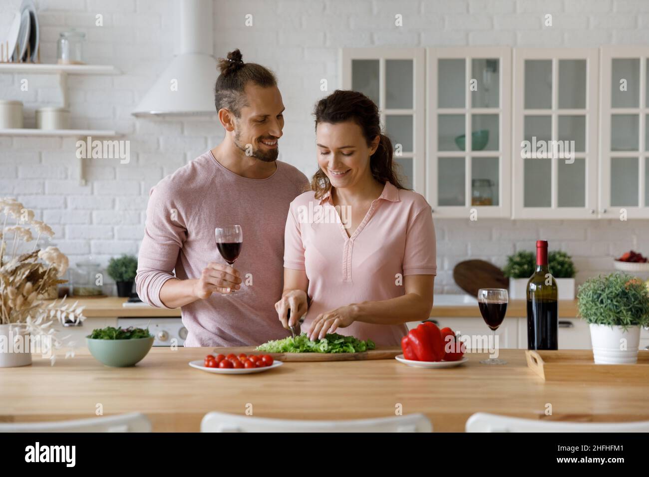 Affectionate young man watching wife preparing food. Stock Photo