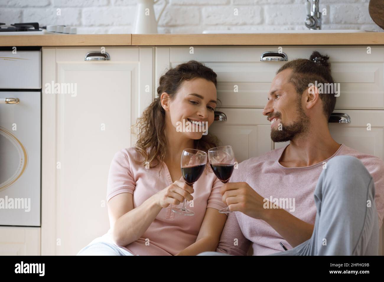 Happy affectionate young couple clinking glasses with wine. Stock Photo