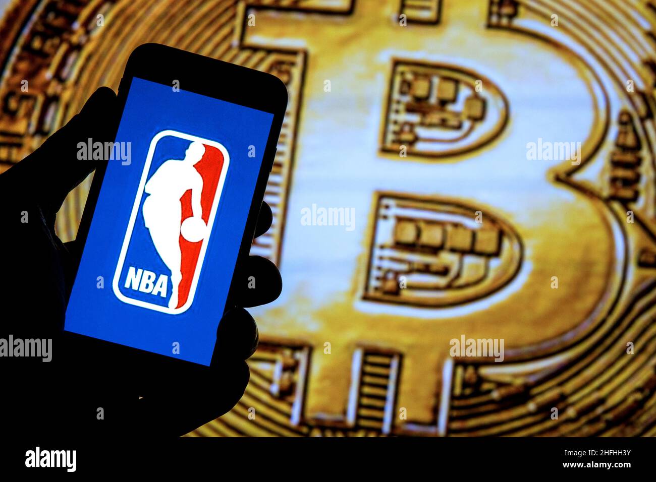 In this photo illustration a NBA logo seen displayed on a smartphone with a Bitcoin in the background. Stock Photo