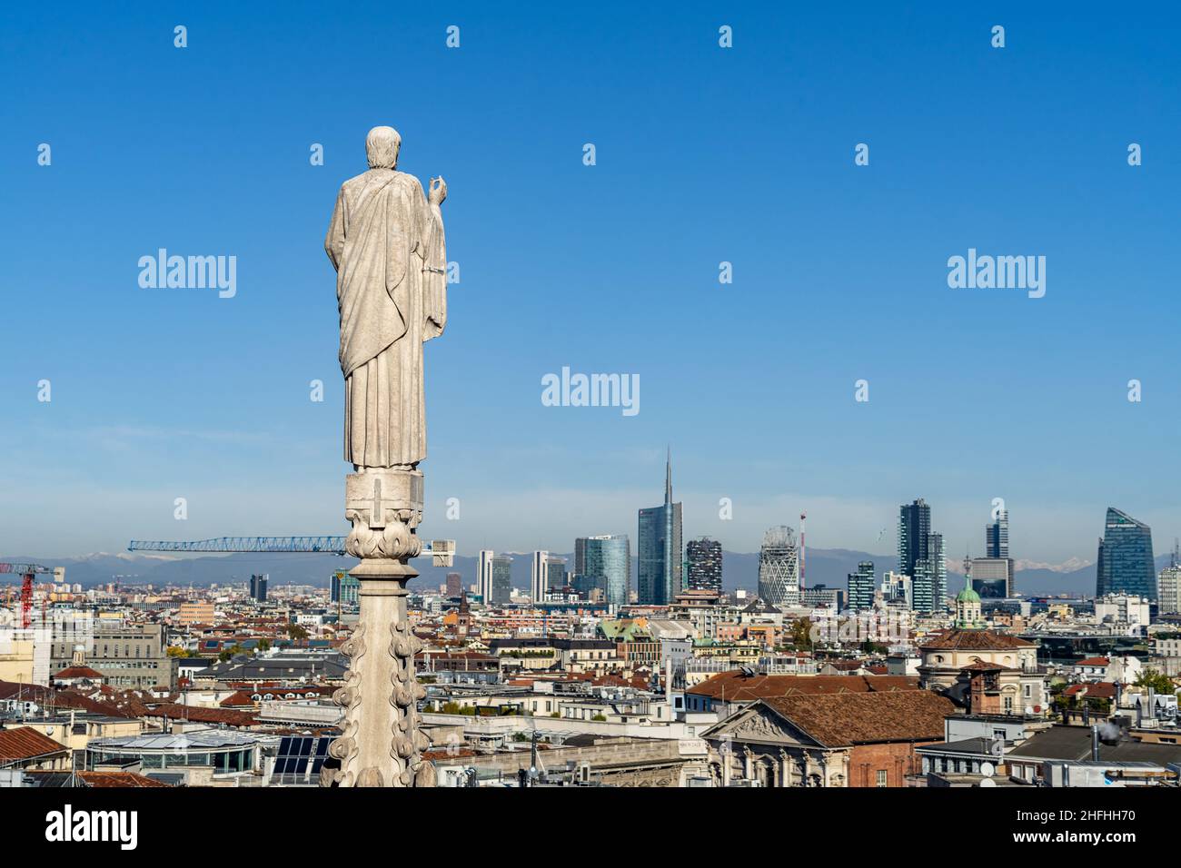 Statue on the top of a spire of Milan Cathedral looking down the city center and skyline, Italy Stock Photo