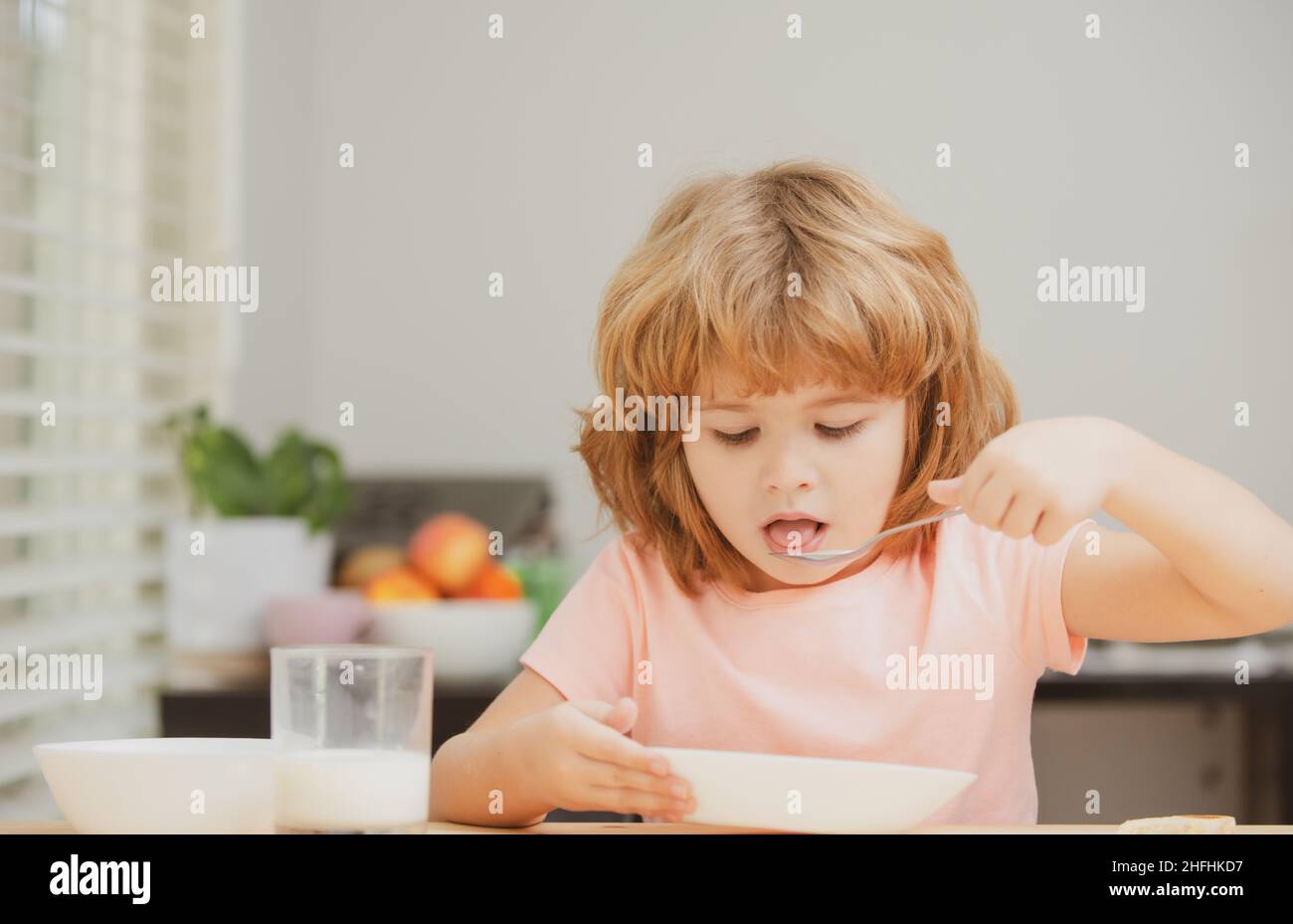 Child eating healthy food at home. Baby eat soup with spoon. Stock Photo