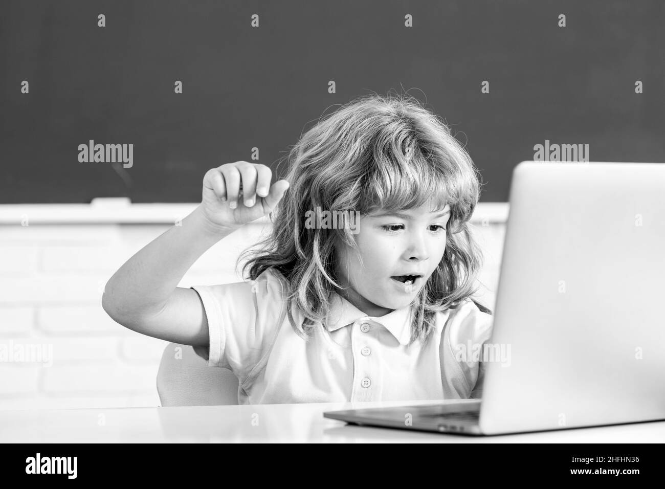 School child using digital pc laptop in class. Portrait of funny pupil of primary school study programming. Online learning technology, virtual Stock Photo