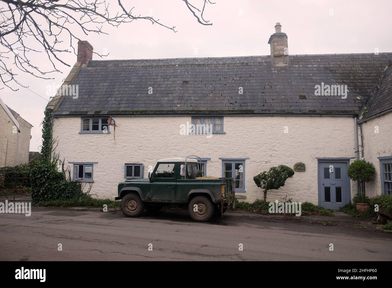 January 2022 - Traditional cottage in the rural Somerset village of Cheddar, with a working Land Rover parked outside Stock Photo