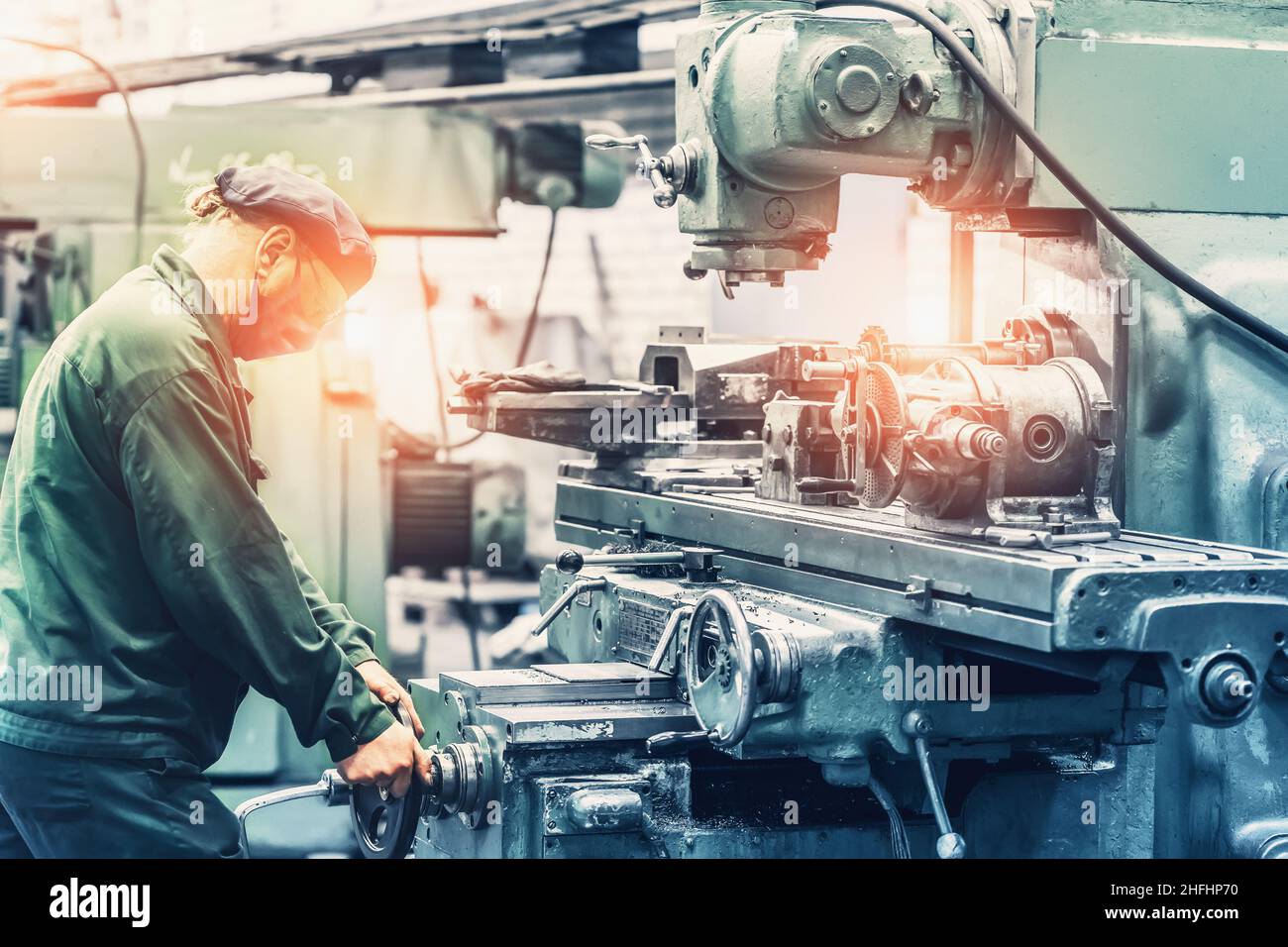 Factory worker using grinder machine tool in metal work factory workshop. Heavy industry manufacturing concept. Stock Photo