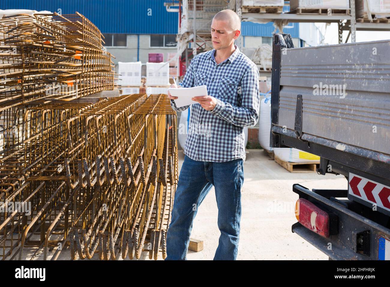 Man worker with papers collecting order at warehouse Stock Photo