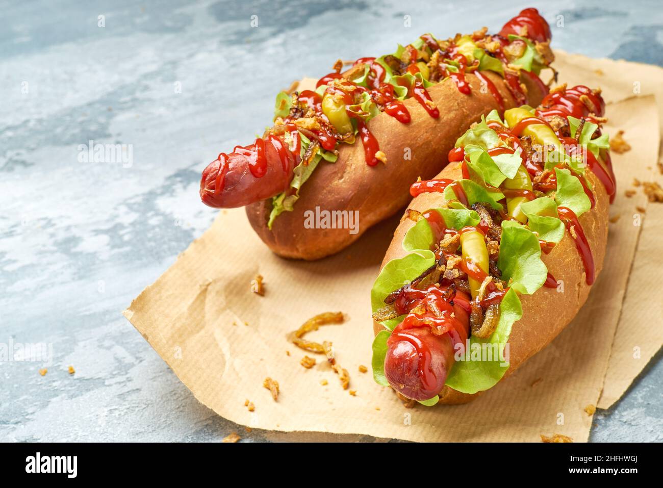 Two delicious hotdogs on craft paper over concrete background Stock Photo