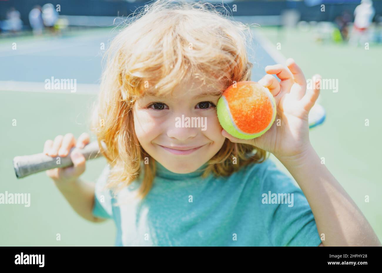 Child with tennis racket and ball on tennis court outdoor. Sport