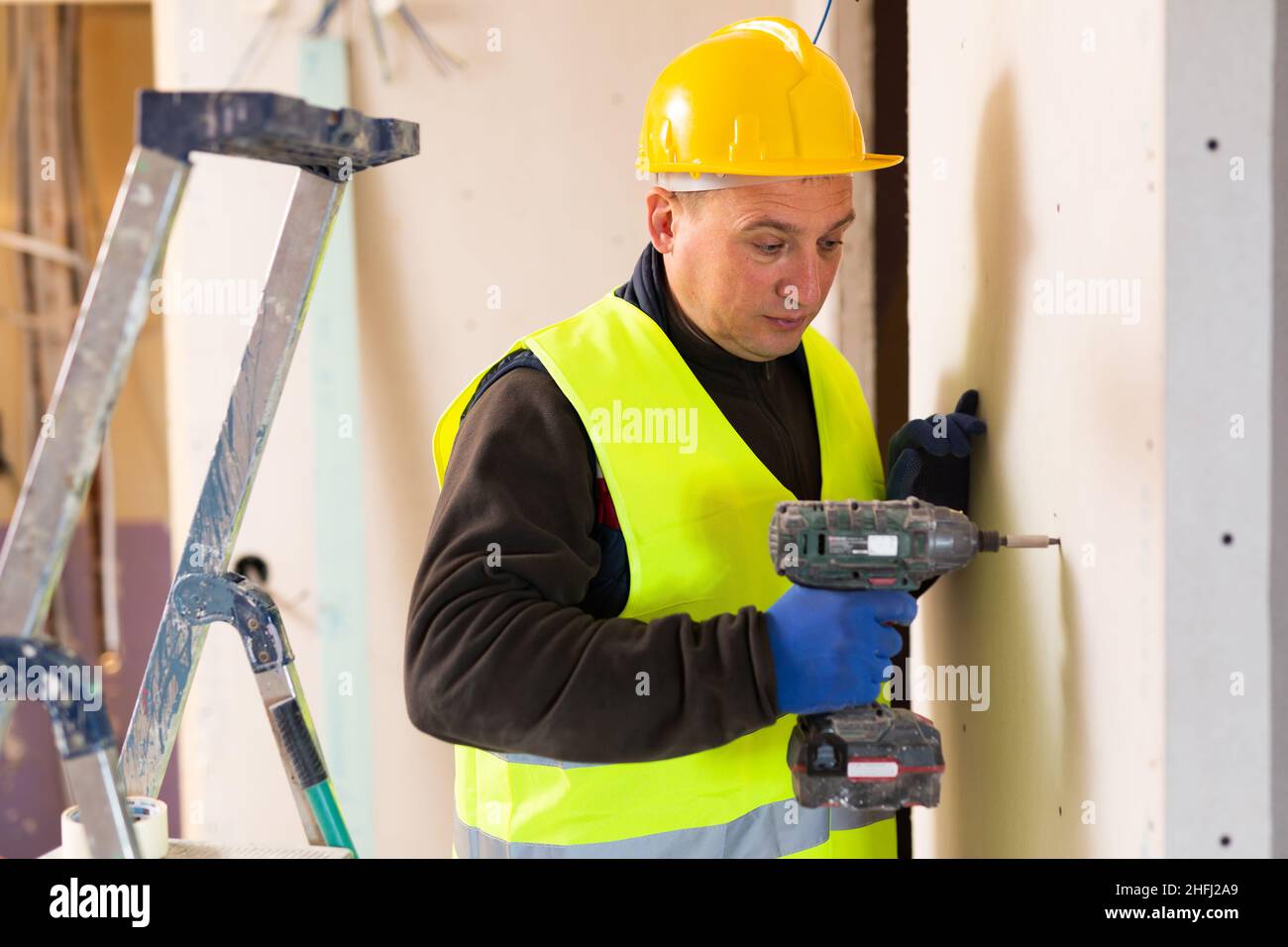 Male contractor holding electric perforator ready for construction works indoors Stock Photo
